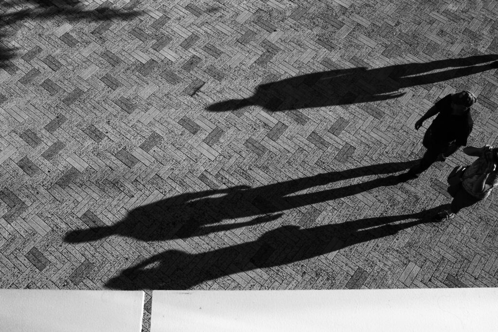 Shadows of people standing on an open plaza